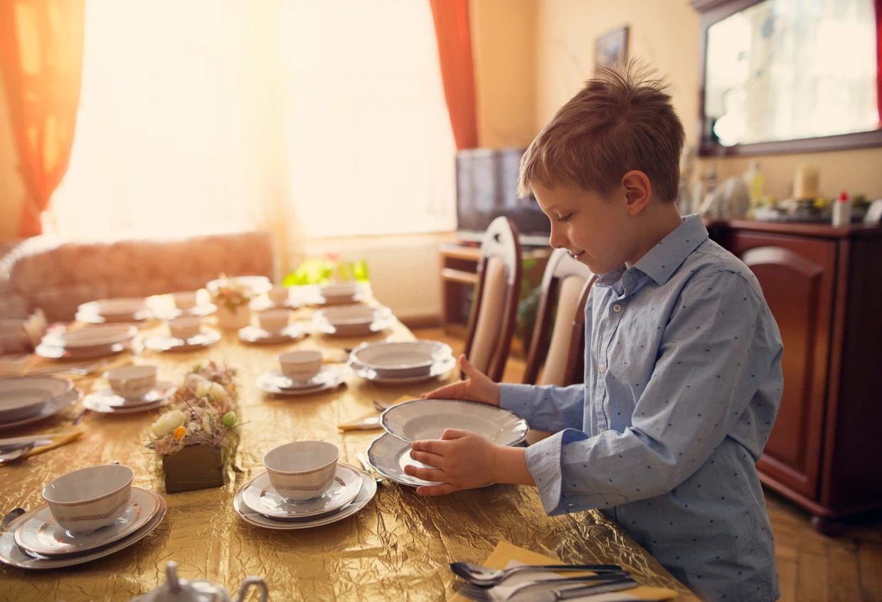 etiquette lessons for kids in Dallas-Fort Worth, iStock image of little boy setting the table before a family meal