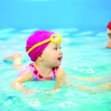 One year baby girl at his first swimming lesson with mother