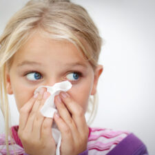 Girl blowing her nose. Space for text. Horizontal, iStock image for article about home treatments, cold remedies