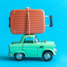 Car with suitcase on top; travel tips and tricks for families