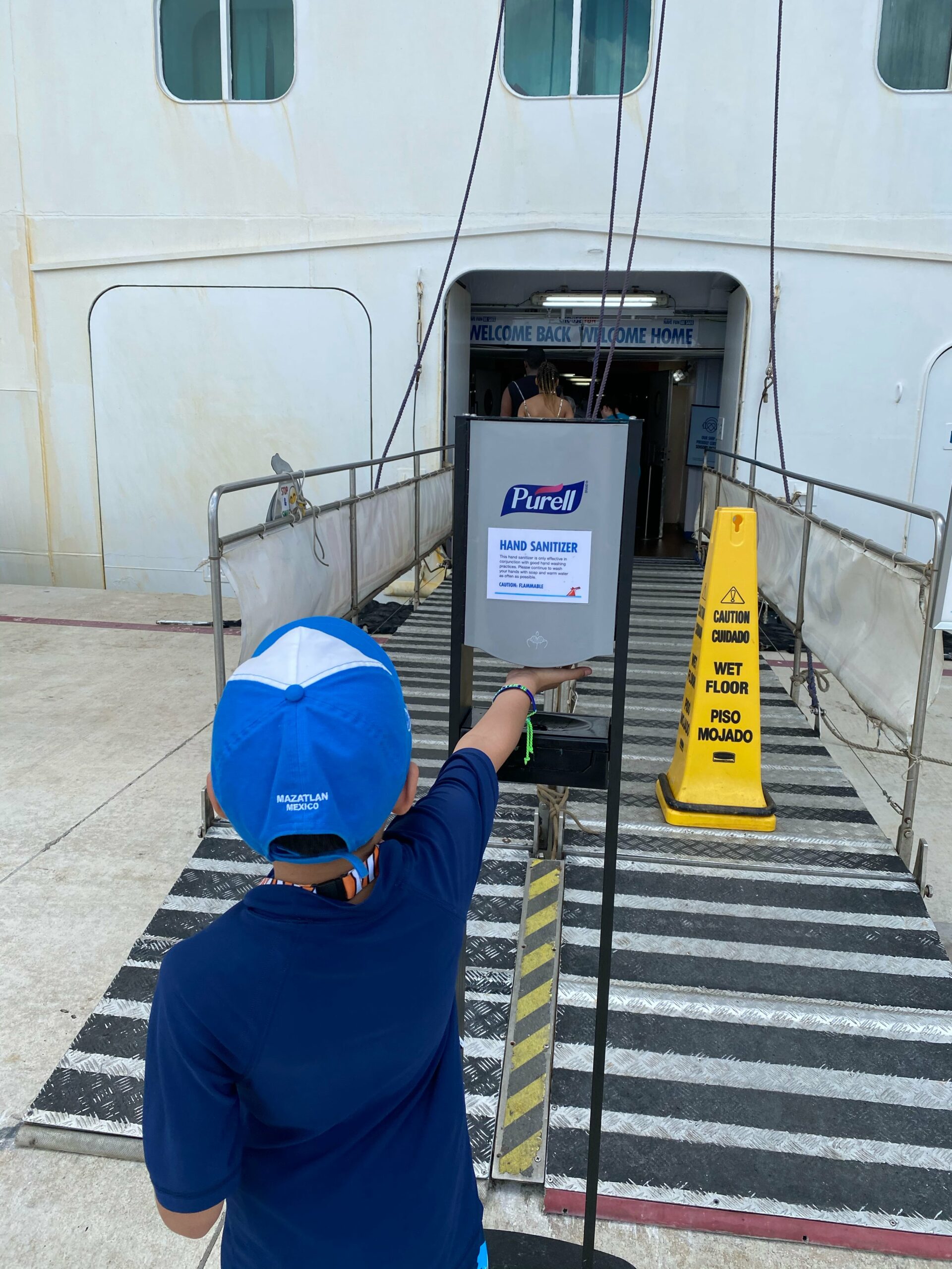 Little boy getting hand sanitizer outside cruise ship during coronavirus outbreak