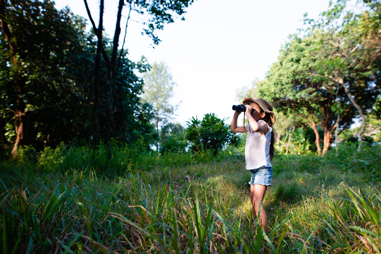 Little girl using binoculars learning about birds