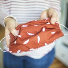 Young woman shows self-made face mask to protect against virus and bacteria