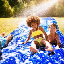 Kids on waterslide in the backyard during summer