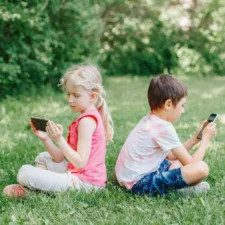 iStock of children at park, watching smartphone screens