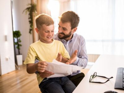 The Right and Wrong Way to Praise Your Child iStock image: Happy father and son looking at fathers paperwork at home office.