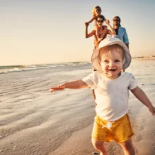 iStock image of toddler and family at the beach, article reviewing ocean and beach safety for kids