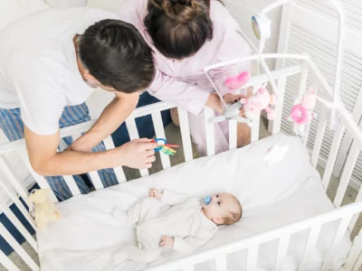 iStock image of mom and dad looking at their baby in a crib, article on safe sleep habits for infants