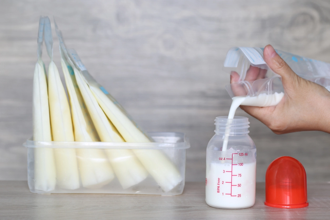iStock image of pouring thawed breastmilk into a baby bottle, for article on common, alternative uses for breastmilk