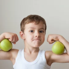 iStock image of boy with apples as biceps, on article about healthy and easy food swaps for kids
