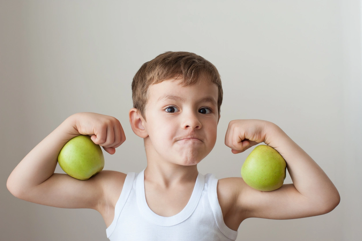 iStock image of boy with apples as biceps, on article about healthy and easy food swaps for kids