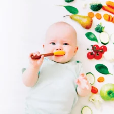 iStock image of baby eating soft, solid foods, for article on how to safely introduce common food allergens to your baby