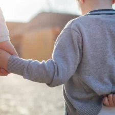 iStock image of a mom and her son walking hand in hand, for article on teaching kids body boundaries and why parents ought to reconsider whether to force their kids to give hugs, even to close relatives