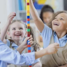 elementary students wearing school uniforms playing with building blocks
