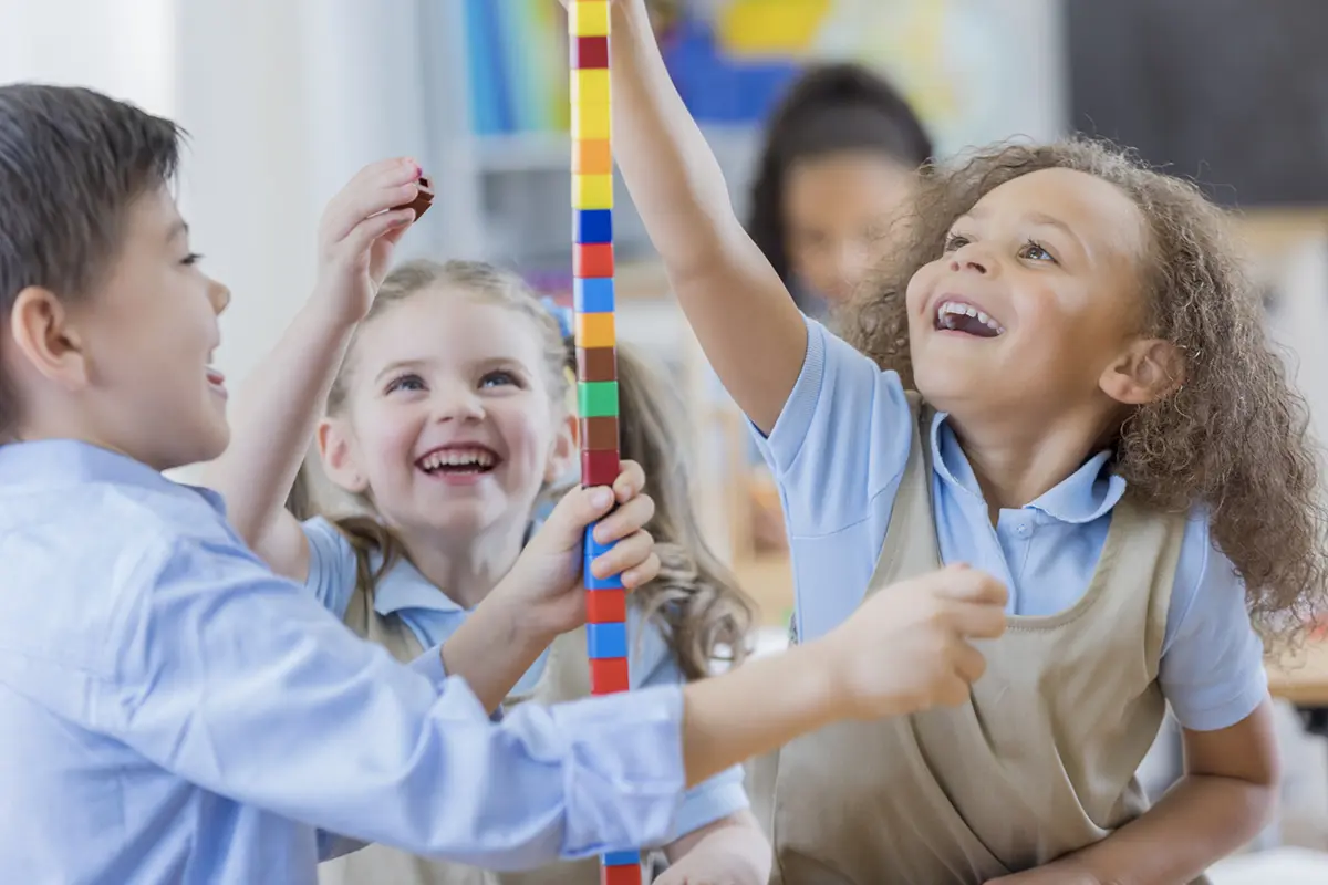 elementary students wearing school uniforms playing with building blocks