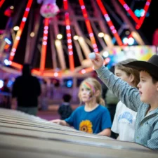 Boy wearing a cowboy hat and other children playing carnival games, at the Fort Worth Stock Show & Rodeo