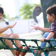 iStock image of little boy and girl on the playground, playing rock paper scissors, for Mentally Strong Kids article on how parents can handle conversations with their kids on first boyfriends or girlfriends