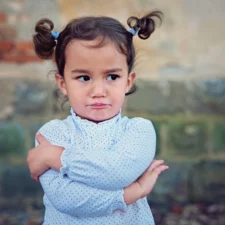 iStock image of little girl pouting with her arms crossed, for column on how parents can respond to their kids when they complain "That's not fair"