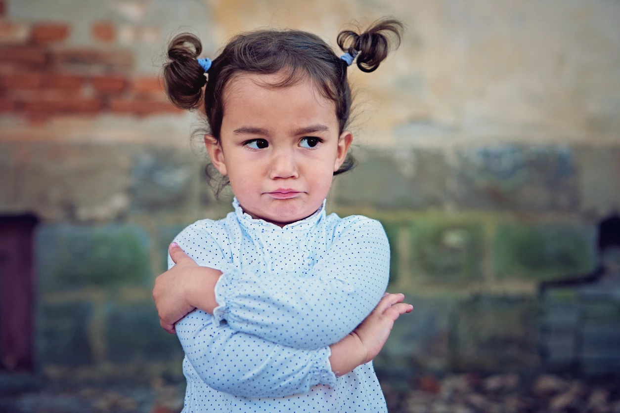 iStock image of little girl pouting with her arms crossed, for column on how parents can respond to their kids when they complain "That's not fair"