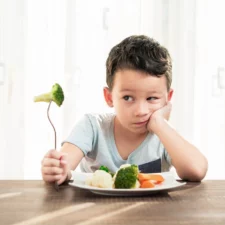 iStock image of a child who's very unhappy with having to eat vegetables, for article on picky eating