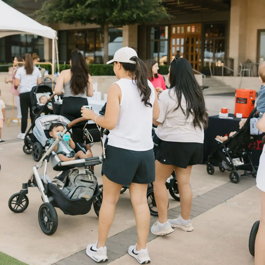 Image of women walking with their young children in strollers, at an event with The Mom Walk Collective groups in Dallas-Fort Worth, photo courtesy @honeylandphoto via Instagram
