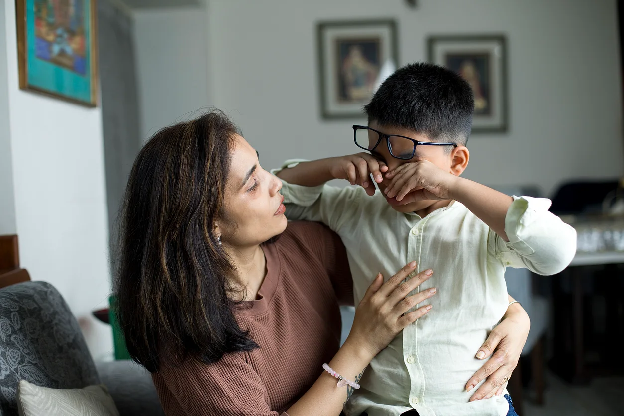 iStock image of a caring mother comforting her little crying son at home, for article on books about bullying to read with your children