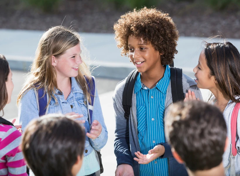 iStock image of students talking outdoors, for article on the 6-7 slang and social trend, with a Dallas counselor's advice for parents on how to set boundaries with their kids who just won't stop