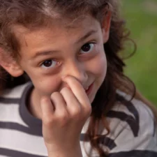 iStock image of young girl picking her nose and smiling