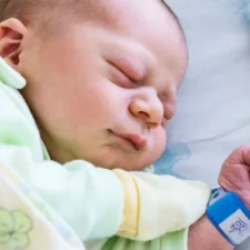 iStock image of a newborn baby after feeding lying on side and sleeping, for article on the most popular baby names of the year