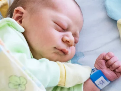 iStock image of a newborn baby after feeding lying on side and sleeping, for article on the most popular baby names of the year