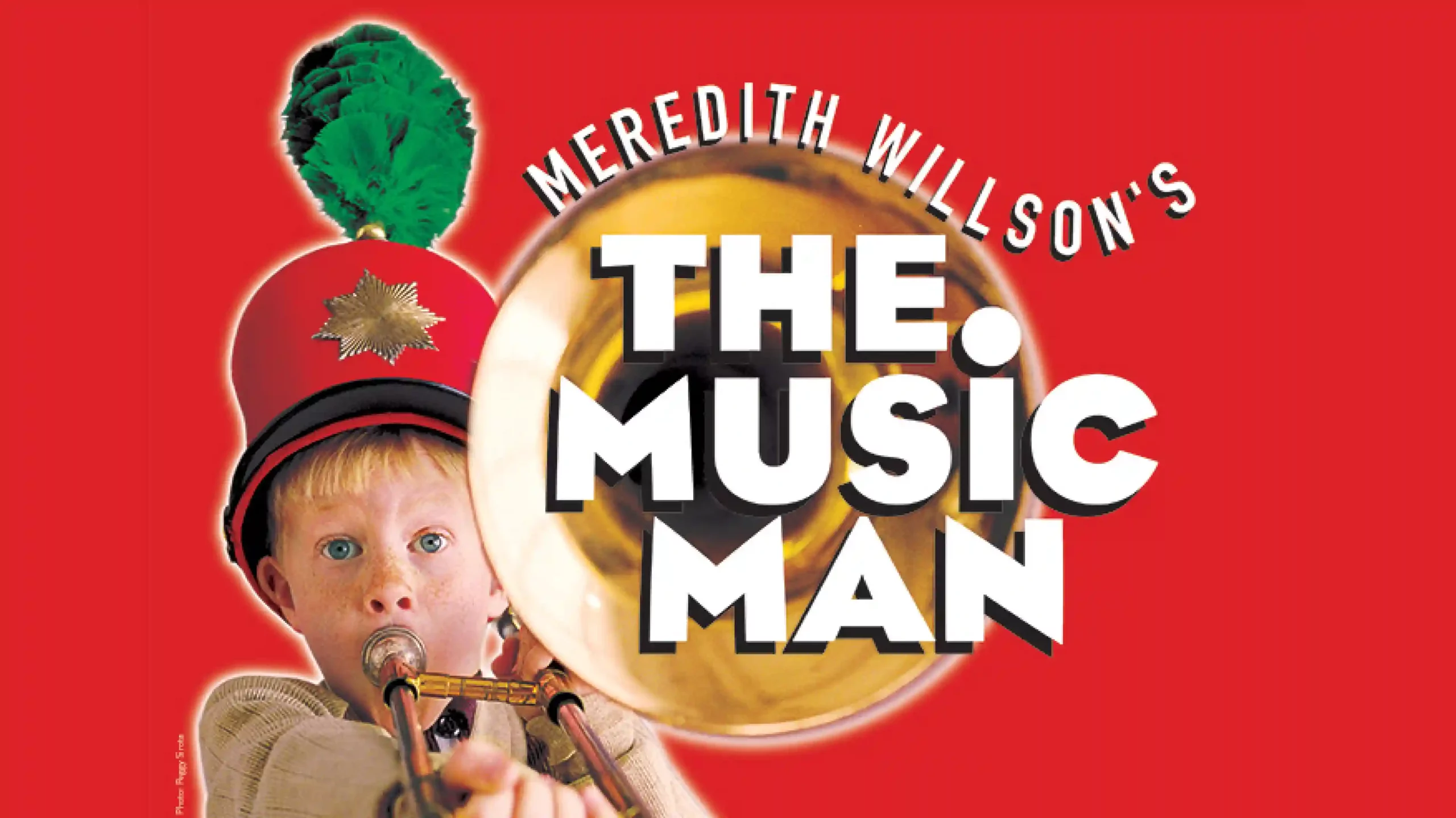 Meredith Willson’s The Music Man title graphic with a child in a marching band hat playing a trombone.