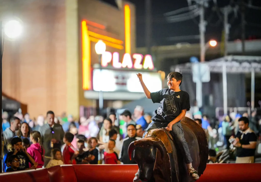 A child riding a mechanical bull in the downtown Carrollton square for the annual TEXFest in Downtown Carrollton