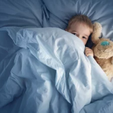 little boy in bed with a stuffed animal, eyes open and not yet asleep