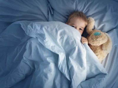 little boy in bed with a stuffed animal, eyes open and not yet asleep