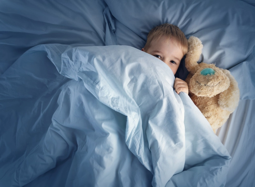 little boy in bed with a stuffed animal, eyes open and not yet asleep
