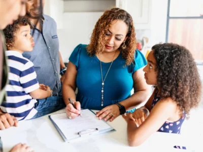 iStock image of mother reading and signing a form, surrounded by her children