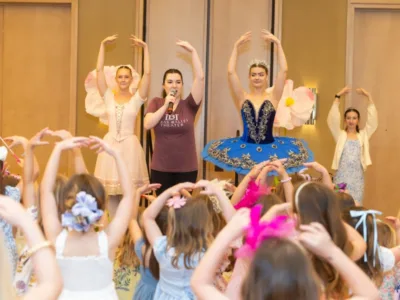 Children following along to ballet poses modeled by ballerinas